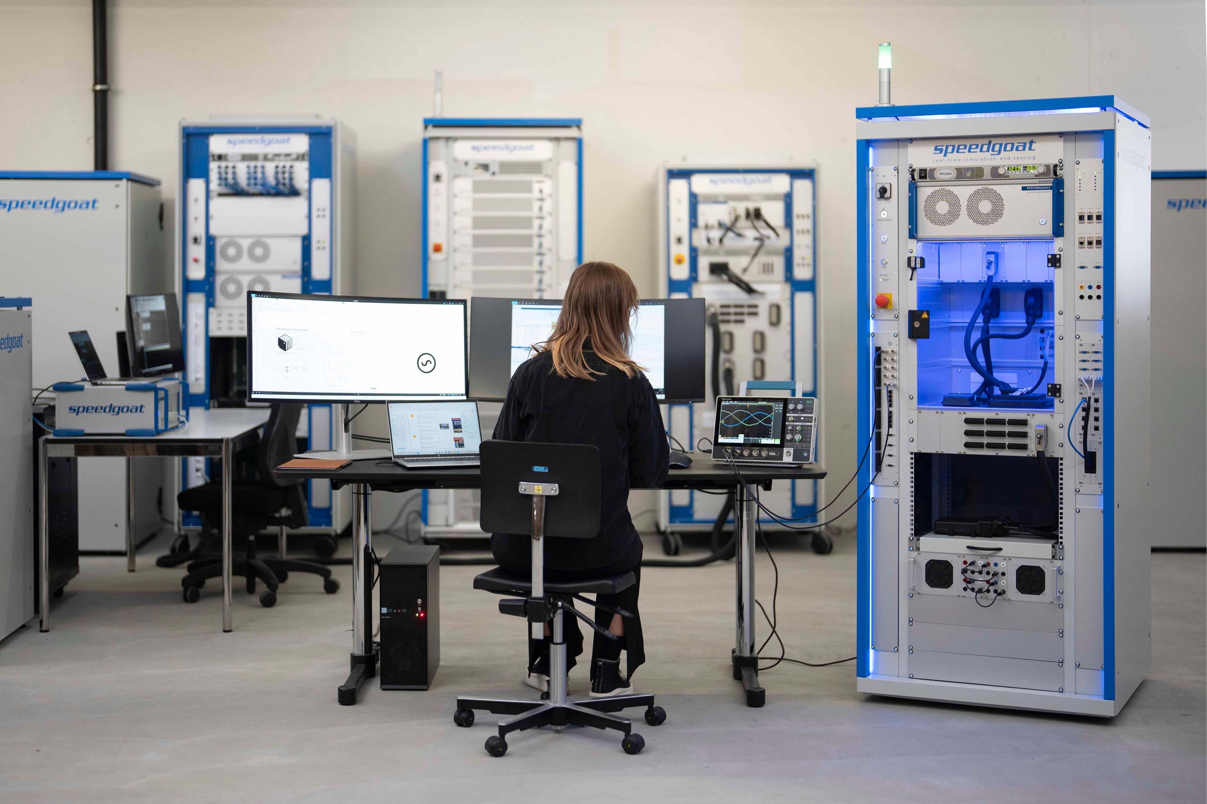 Person adjusting electronic test equipment at a laboratory workstation.
